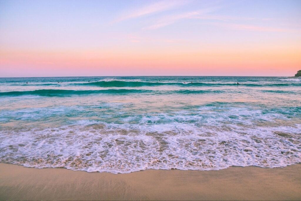 Stunning sunset over the clear waters of Roatán Beach, with gentle waves lapping the shore, showcasing the tropical beauty of the island