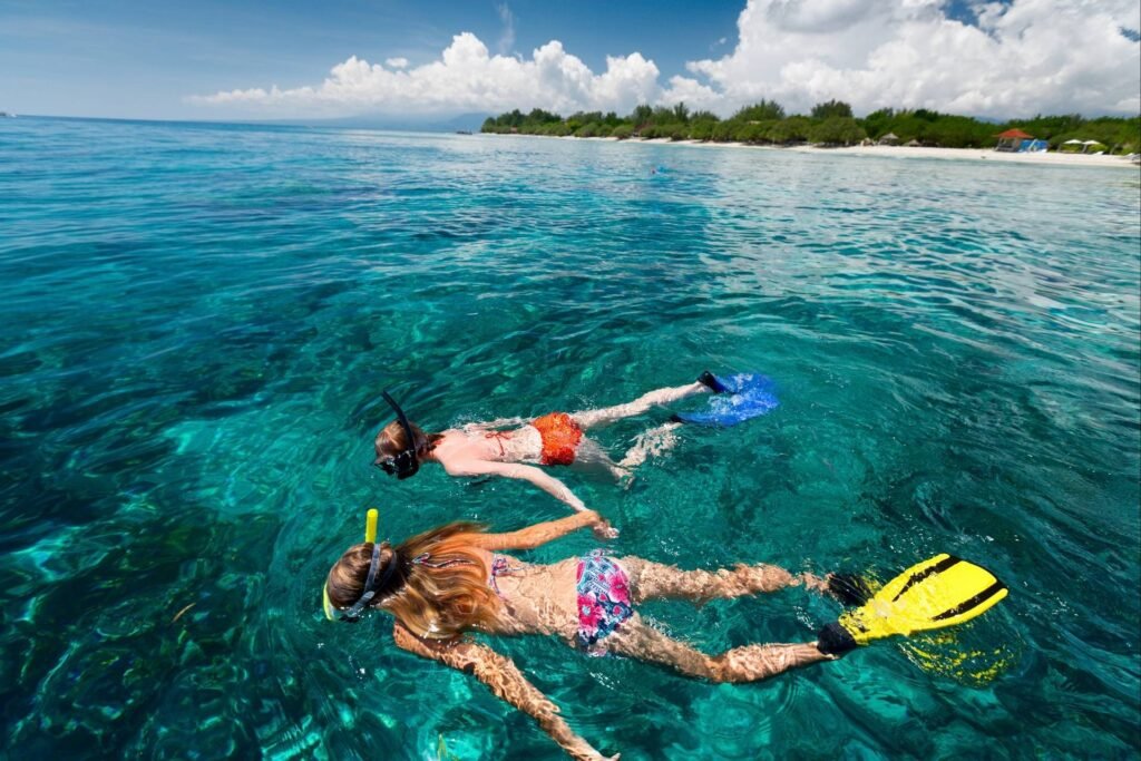 Two people snorkeling in the crystal-clear waters of Roatán, surrounded by vibrant marine life, showcasing one of the island’s top activities for adventure lovers.