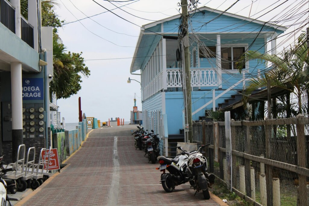 Charming street view in Utila, Honduras, with colorful Caribbean houses and parked motorbikes near the coast.